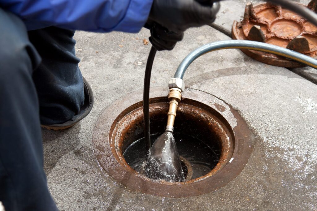 Plumber hydro jetting a sewer line through a manhole in Bonita Springs