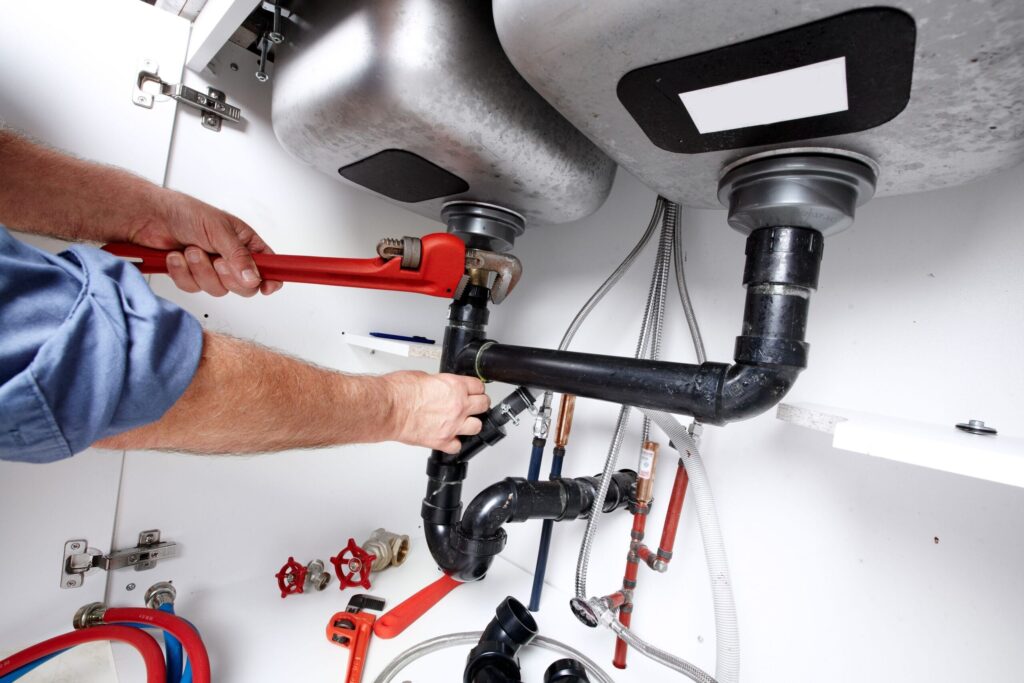 Plumber repairing drain pipes beneath a kitchen sink in Bonita Springs